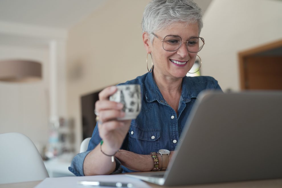 portrait of a 55 year old senior woman working on her laptop in her home