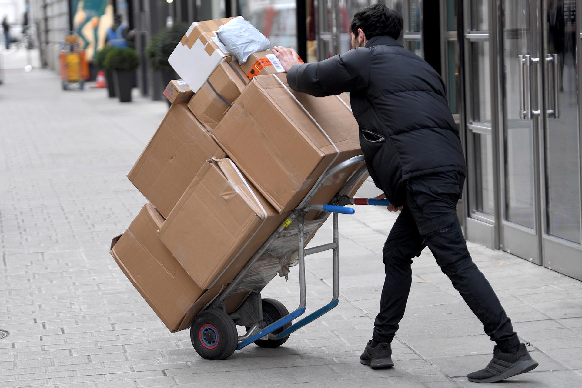 Ein Paketzusteller mit Sackkarre. Die Arbeitsbedingungen bei den Paketdiensten sind unmenschlich.