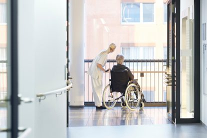 Eine Pflegekraft steht neben einer Frau im Rollstuhl in einem Krankenhaus. In Österreich herrscht ein Pflegenotstand.