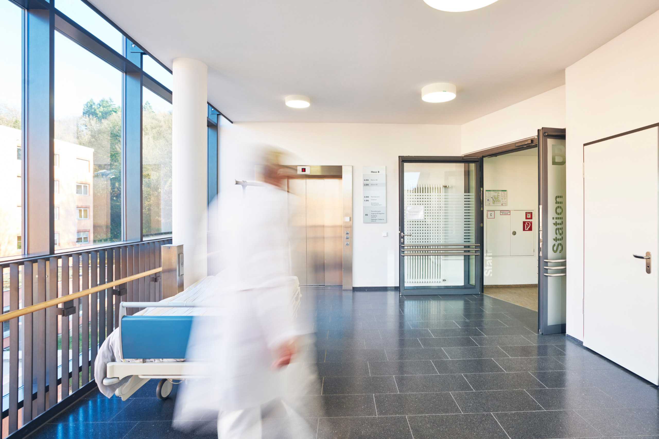 Ein Arzt in einem Krankenhaus ist nur schemenhaft zu sehen. Er läuft an einem Krankenbett vorbei. In Österreich herrscht ein Pflegenotstand.