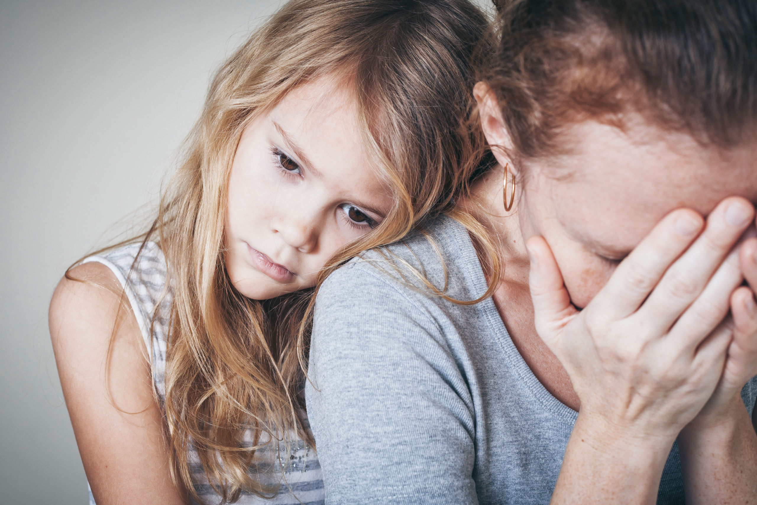 Alleinerziehende Mutter weint und wird von Tochter getröstet. 