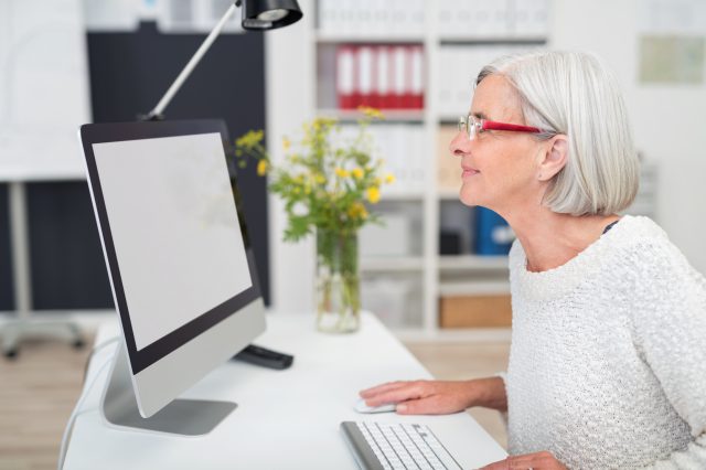 ältere frau im büro schaut auf computer, ältere Arbeitnehmer:innen