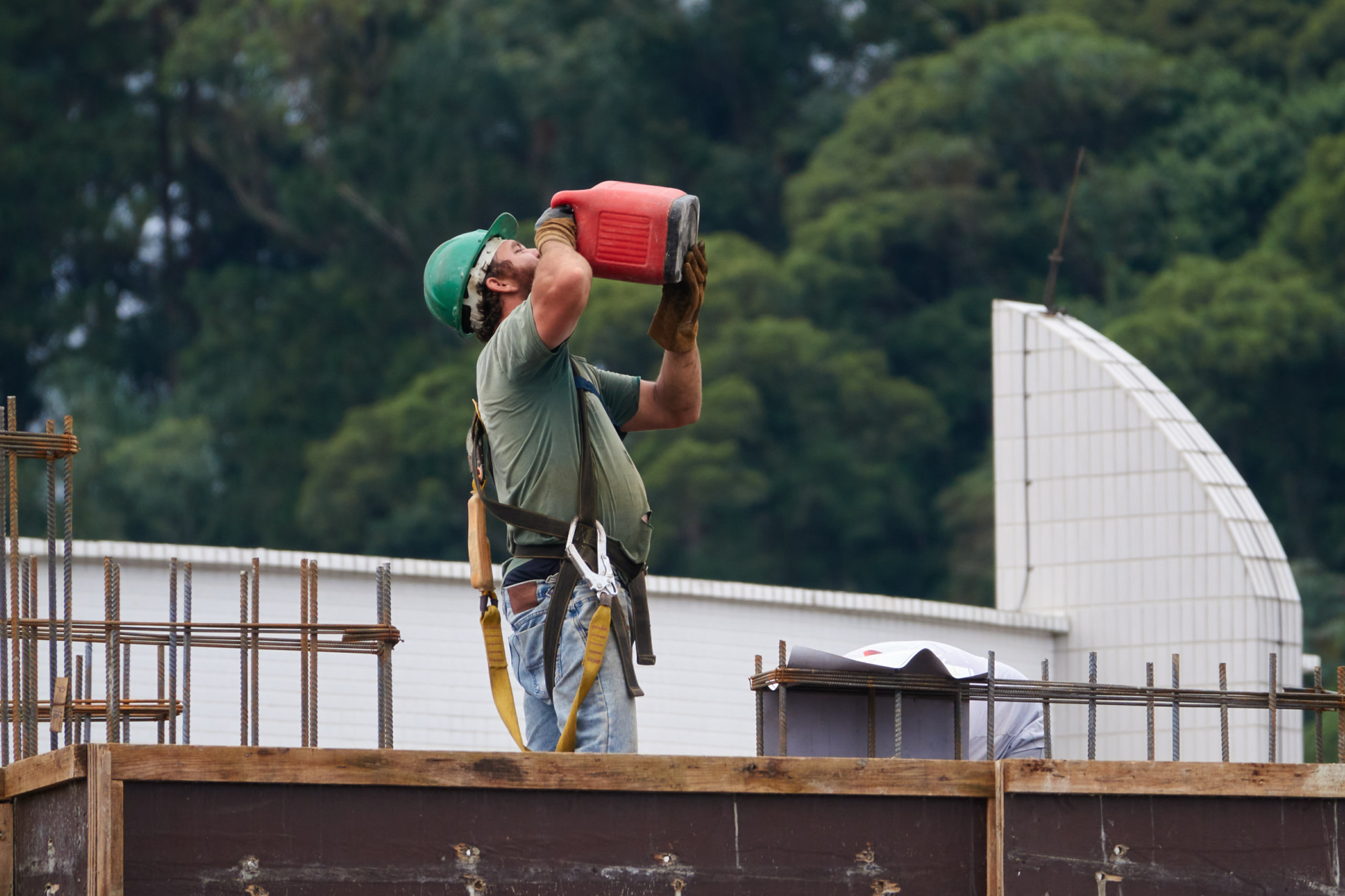 Ein Bauarbeiter trinkt auf einer Baustelle bei große Hitze Wasser aus einem Kanister. Die Hitze-App soll helfen.