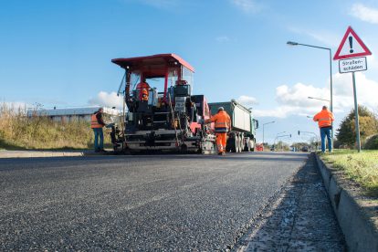 Bauarbeiter verlegen Straßenbelag in großer Hitze. Die Hitze-App soll helfen.