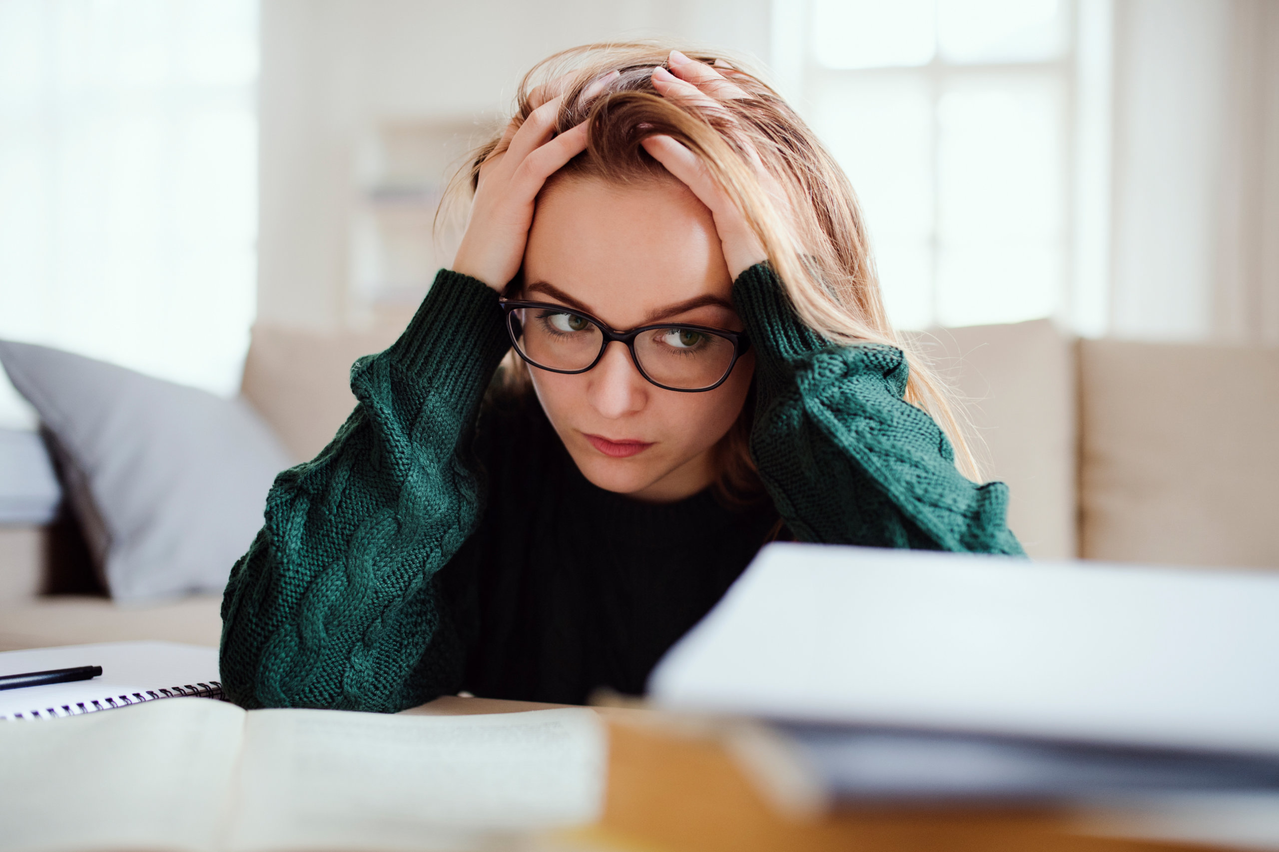 Eine Studentin verzweifelt über ihrem Studium. Wegen der Inflation kann sie es sich nicht mehr leisten.