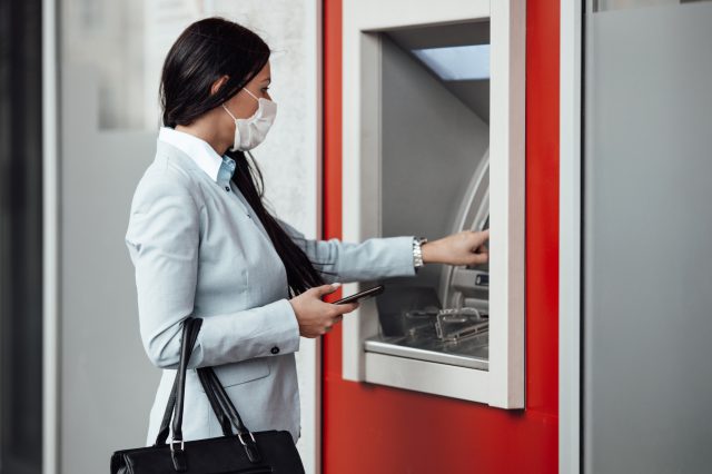 Frau hebt Geld an einem Geldautomaten ab. Symbolbild: Reallohnverlust in Österreich