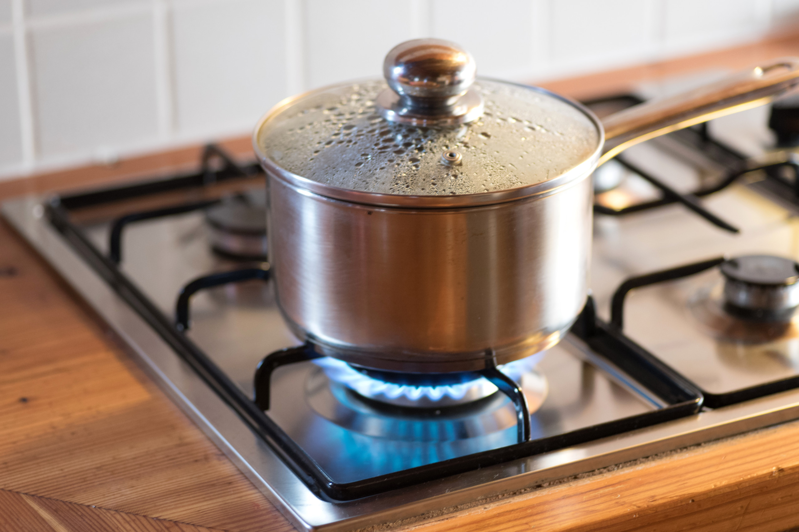 Topf mit kochendem Wasser und Deckel drauf auf einem Gasherd. Symbolbild: Energie sparen