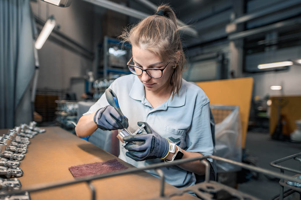 Eine Frau arbeitet bei TCG Unitech GmbH an einer Werkbank. Symbolbild für KV-Verhandlungen der Metaller.