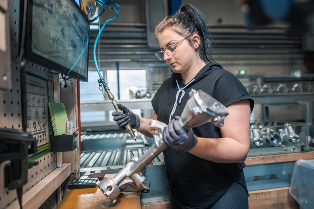 Eine Frau an einer Werkbank in der Industrie bei TCG Unitech GmbH. Symbolbild für KV-Verhandlungen der Metaller.