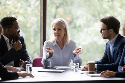 Eine Frau als Managerin spricht am Konferenztisch in einem Meeting zu ihren Kollegen. Symbolbild für die Frauenquote in der EU.