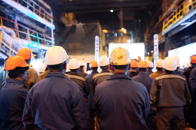 Der Rücken vieler Arbeiter mit Helm ist zu sehen. Streik nach dem Scheitern der Metaller KV-Verhandlungen 2022.