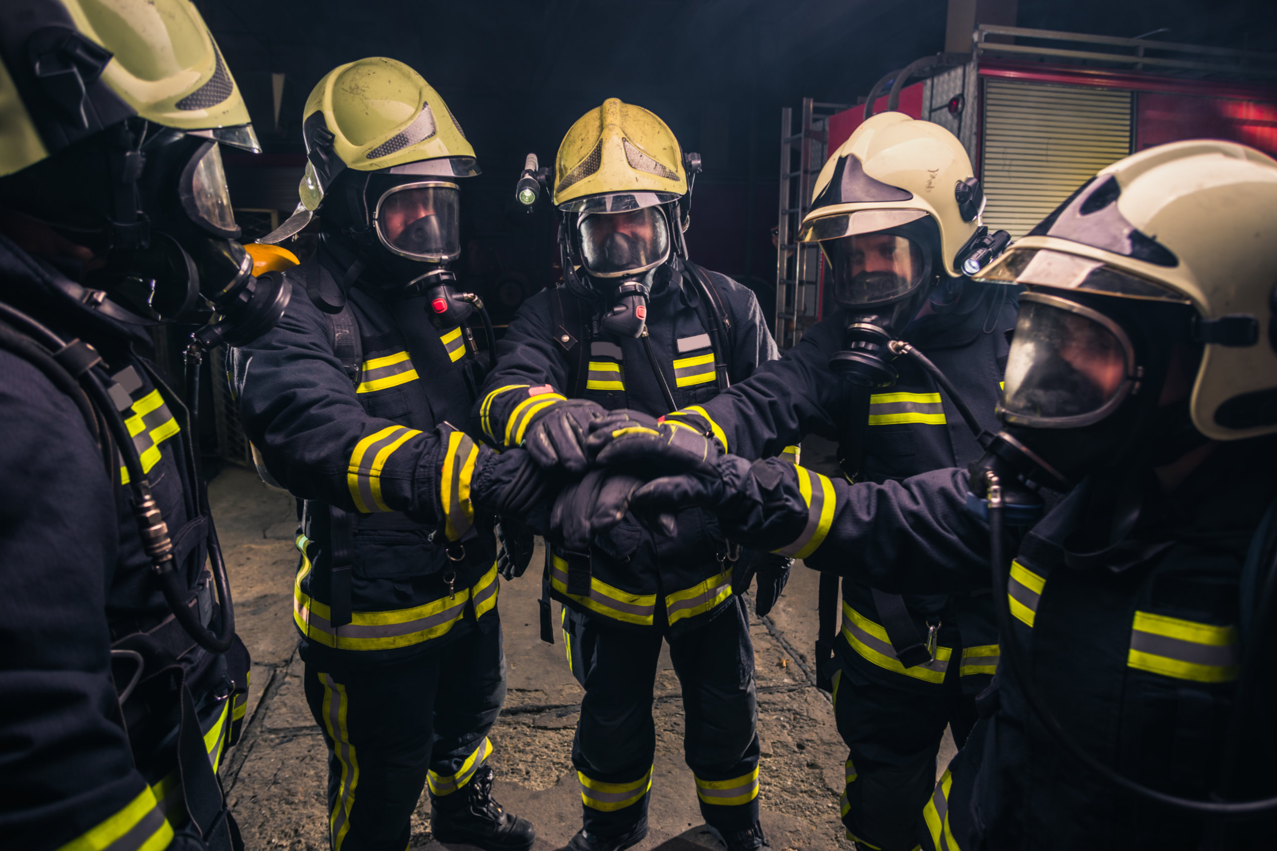 Feuerwehrleute mit Atemmaske geben sich die Hände. Symbolbild für KV-Verhandlungen für das Sicherheitspersonal.