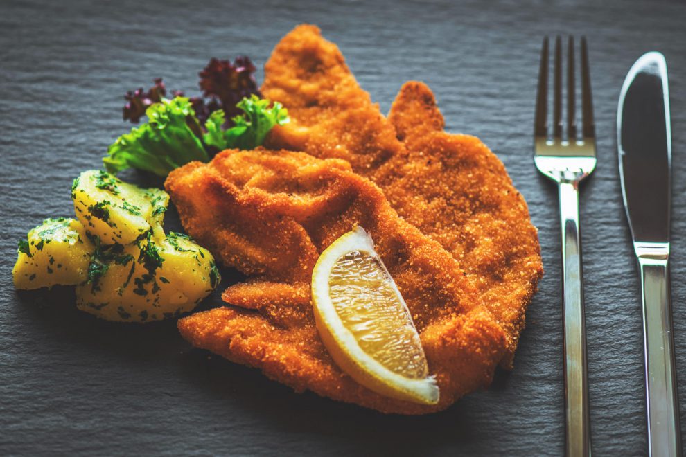 Ein Wiener Schnitzel mit Besteck und Petersielkartoffeln. Symbolbild für den Wohlstandsbericht 2022.