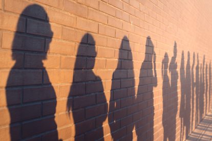 Schatten von Personen, die arbeitslos sind, an einer Wand. Symbolbild für AMS-Zwischenparken.