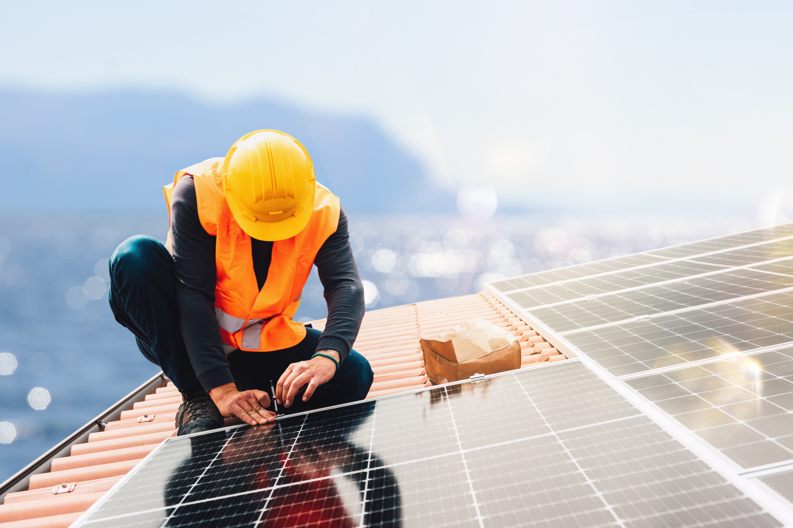 Ein Bauarbeiter montiert eine Solaranlage auf einem Dach. Symbolbild für das Budget 2023.