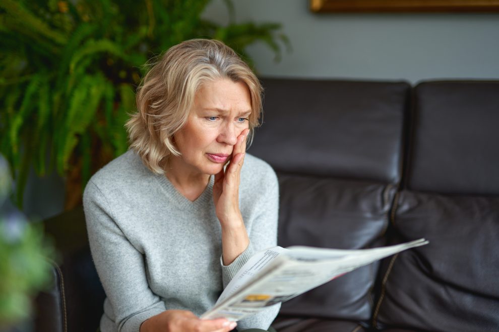 Eine Frau liest mit verzweifeltem Blick eine Zeitung. Symbolbild für das sinkende Vertrauen in die Politik.