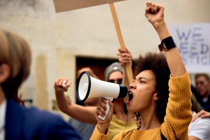 Eine Frau schreit während einer Demonstration in ein Megafon.