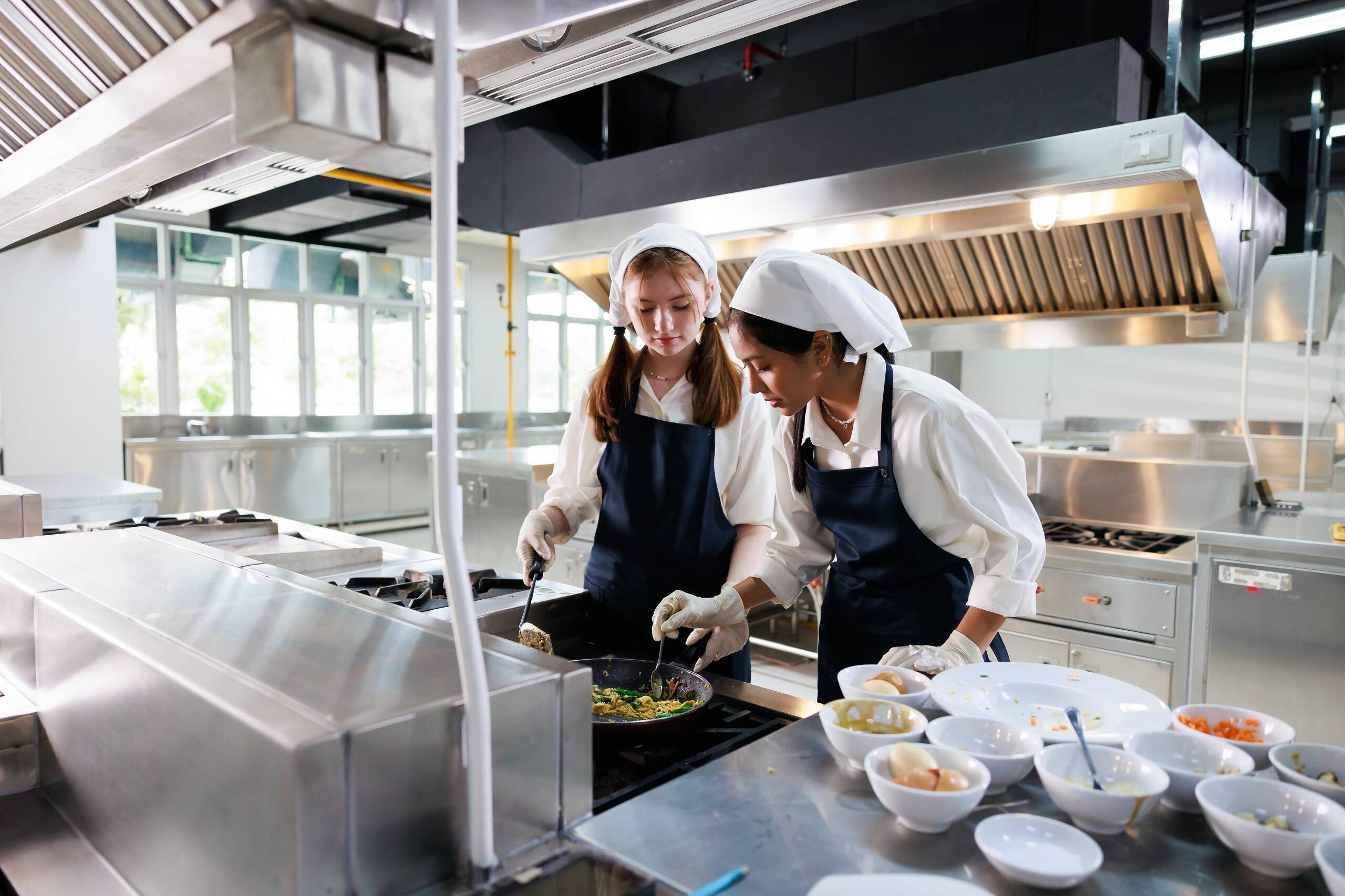 Zwei junge Köchinnen bei ihrer Arbeit in einer Großküche. Geringe Löhne und schlechte Arbeitszeiten in der Gastronomie sind der Grund für den Arbeitskräftemangel.