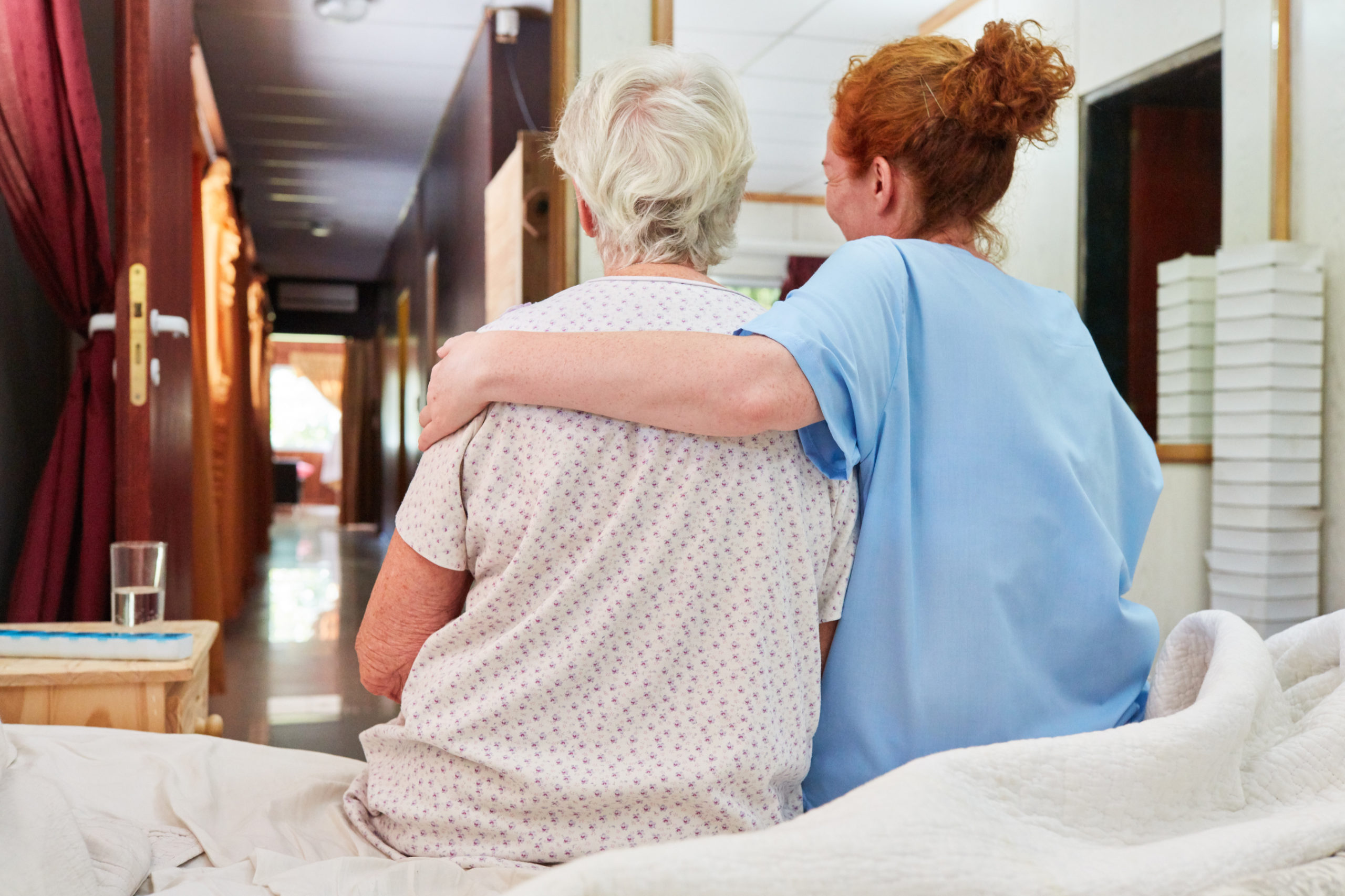 Eine Pflegerin hat eine ältere Frau im Arm. Symbolbild für die Schwerarbeit in der Pflege.