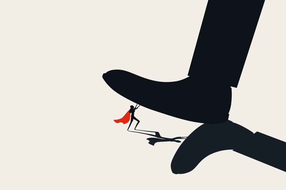 Ein Fuß tritt auf eine Comicfigur mit einem roten Superheldencape. Symbolbild für die Unterdrückung von Betriebsräten in Unternehmen.