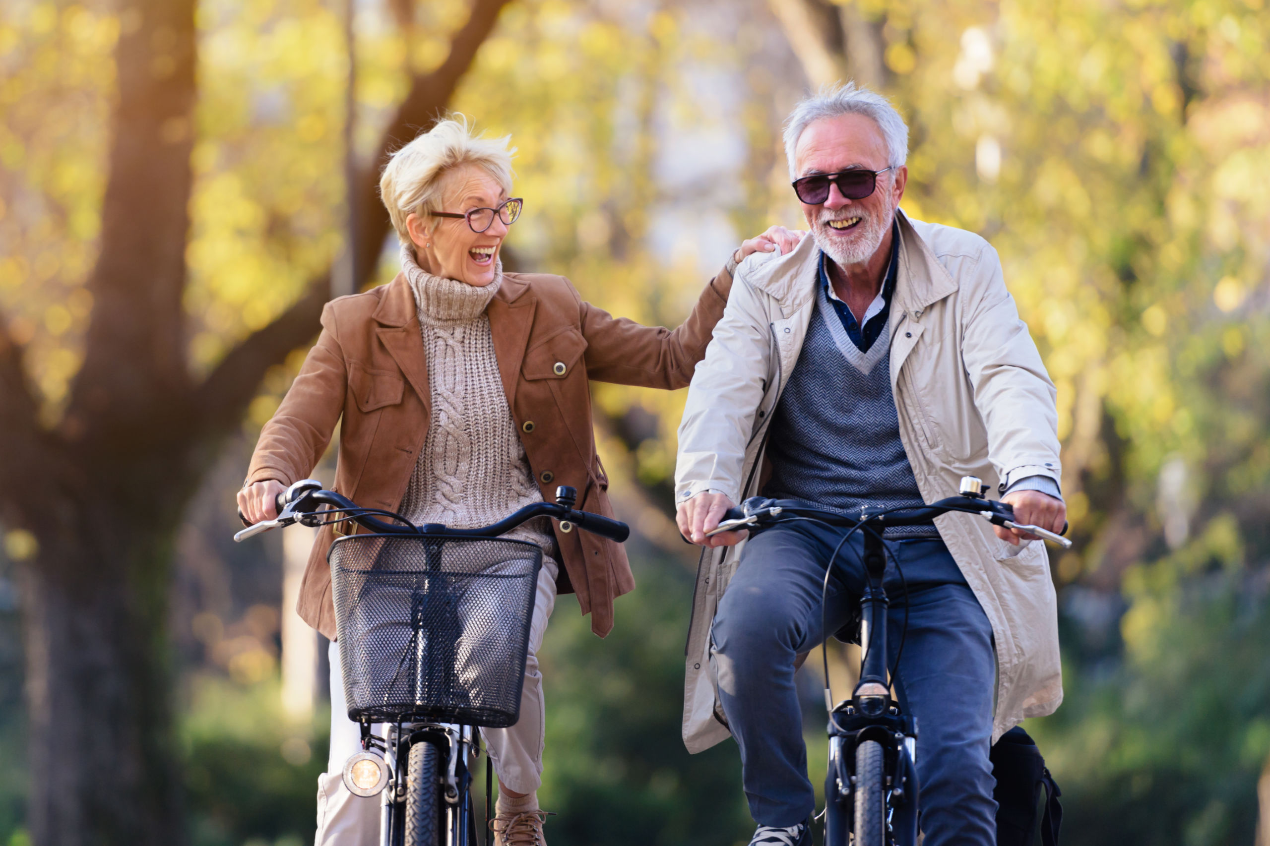 Ein älteres Paar fährt Fahrrad und lacht dabei. Symbolbild für gesunde Jahre im Alter.