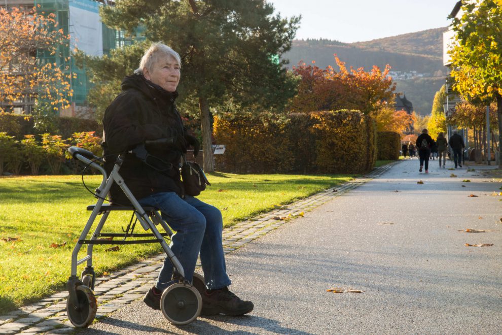Eine ältere Frau lehnt auf einem Rolllator. Symbolbild für gesunde Jahre.