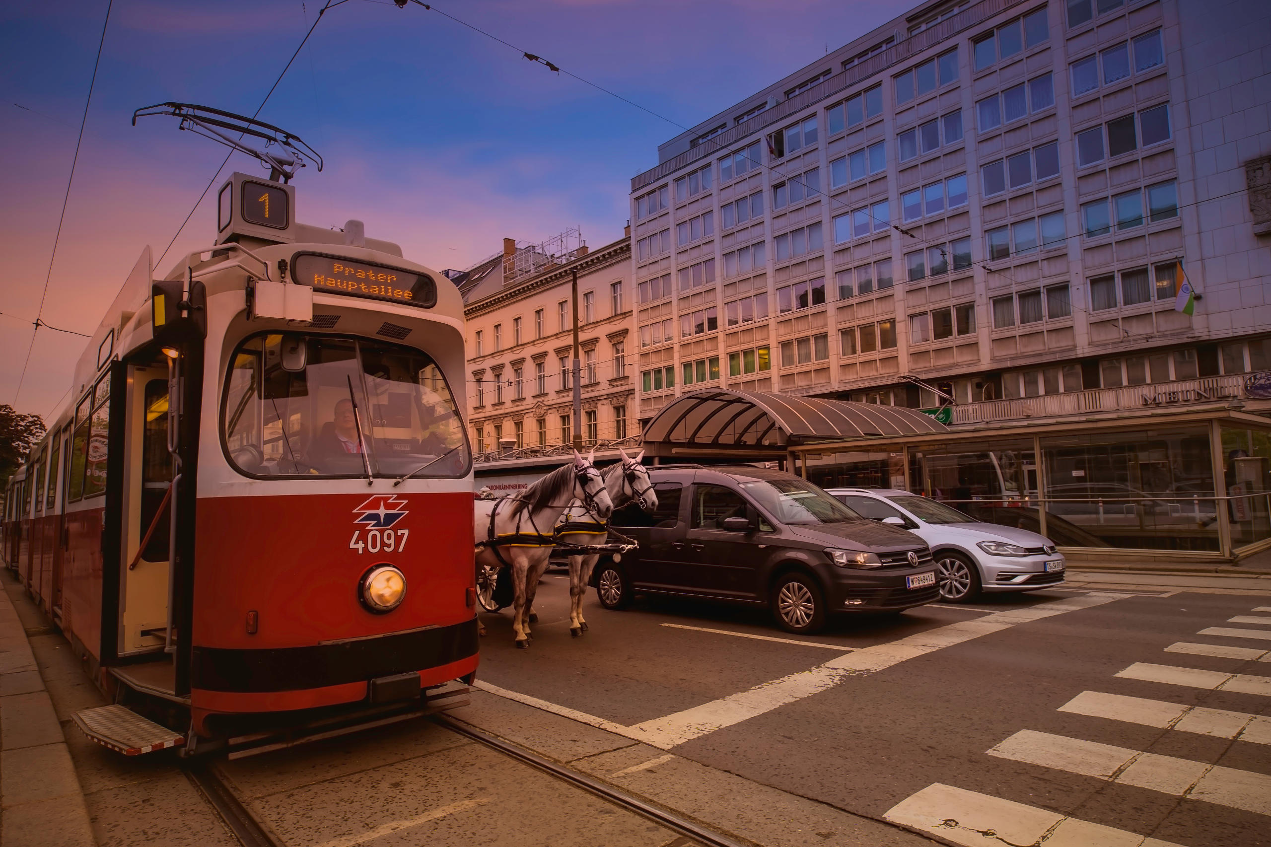 Eine Straßenbahn, oder Bim, steht in Wien an der Ampel. Daneben zwei Autos und ein Fiaker oder Pferdekutsche. Symbolbild für Inflation 2022 in Österreich.