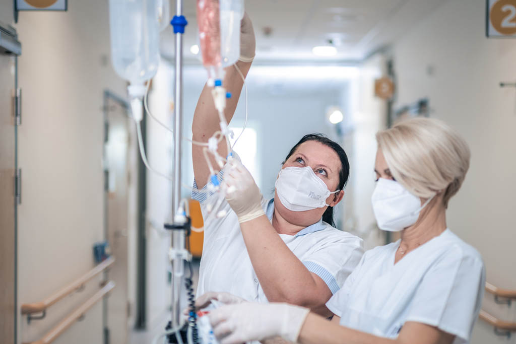 Zwei Pfleger:innen im Hanusch-Krankenhaus arbeiten an einem Infusionsständer.