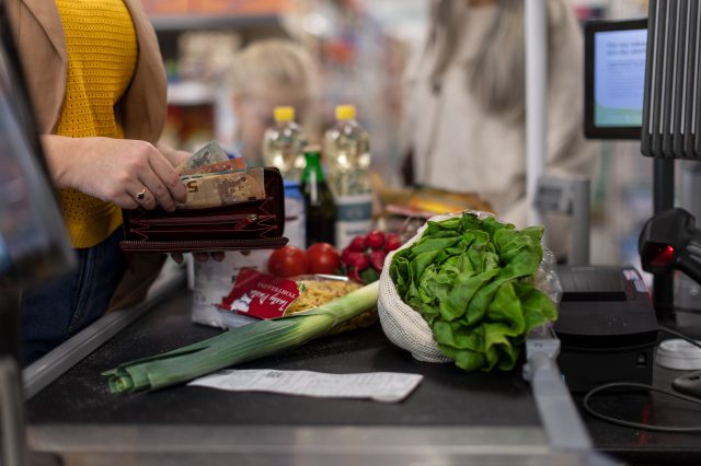 Eine Frau zahlt an der Kasse vom Supermarkt. Die Inflation steigt auf 11,1 Prozent.