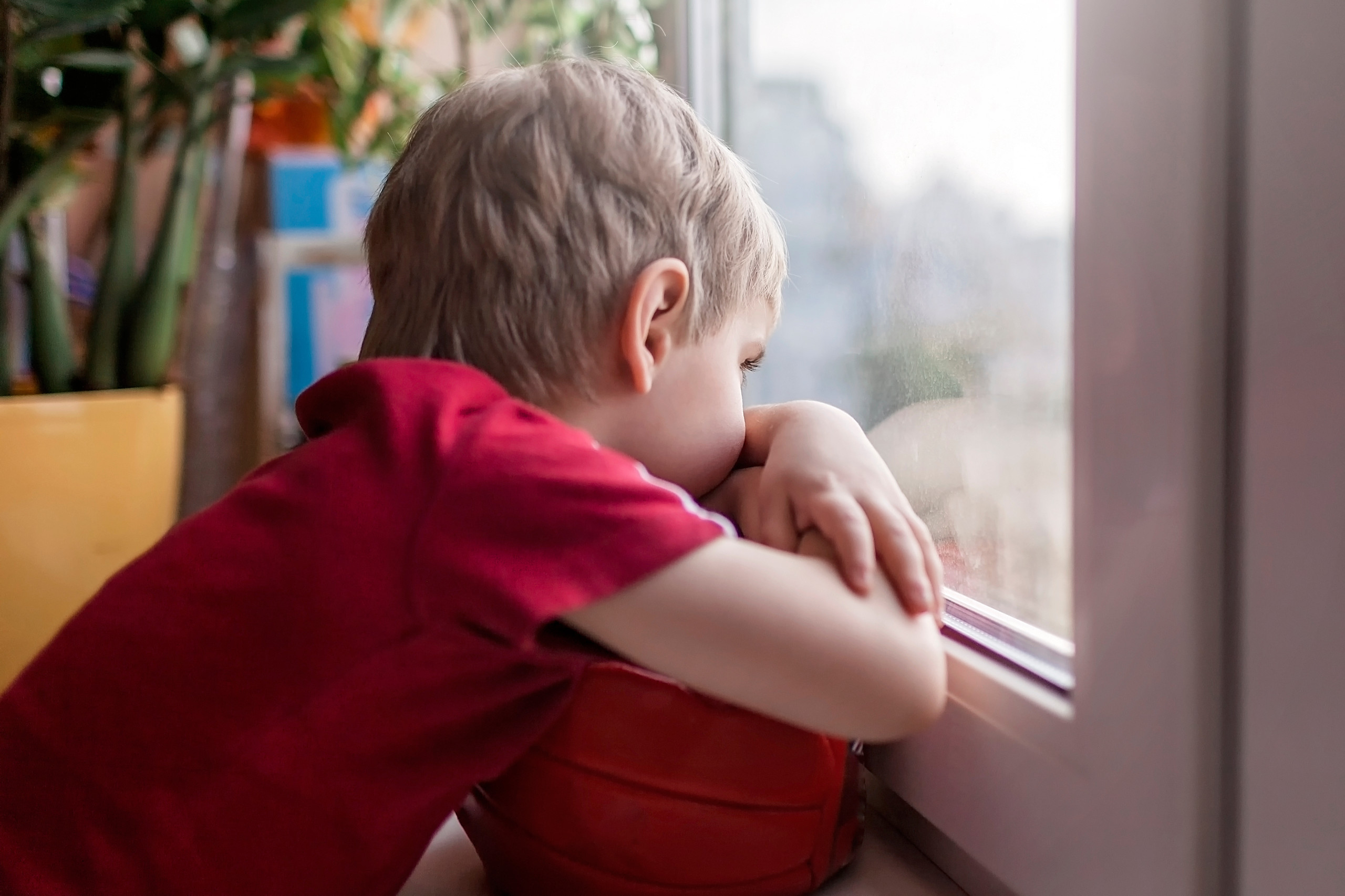 Ein Kind blickt traurig aus dem Fenster. Symbolbild für Kinderarmut.
