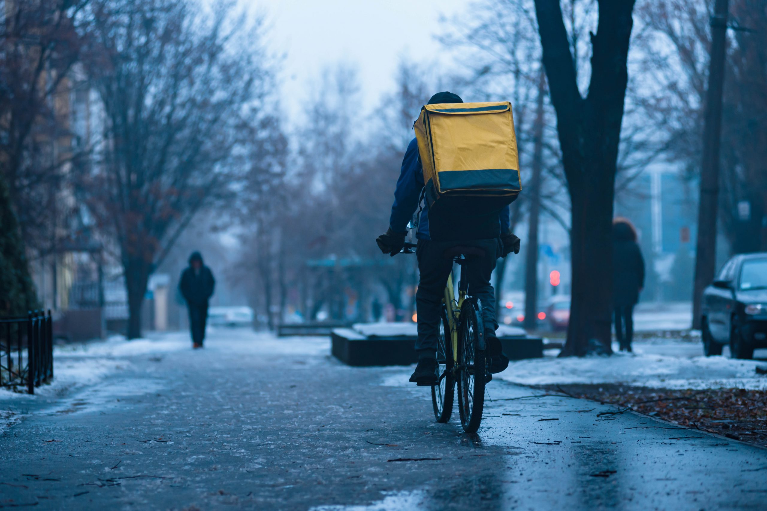 Ein Fahrradkurier fährt bei schlechtem Wetter Essen aus. Symbolbild für prekäre Arbeitsplätze.