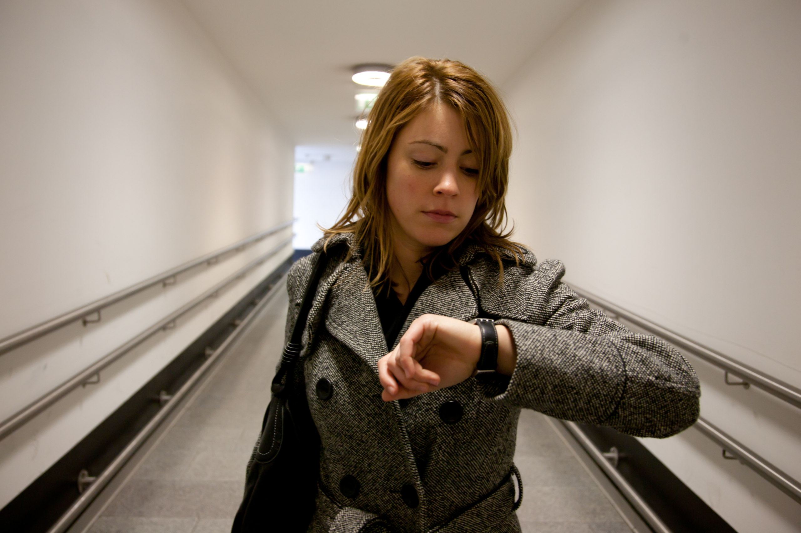Eine Frau schaut auf die Uhr. Symbolbild für die Arbeitszeitverkürzung in Österreich. Stechuhr.