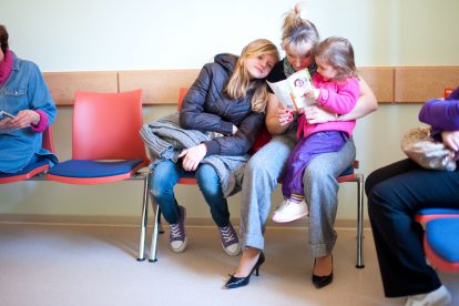 Eine Mutter mit zwei Kindern bei einem Arzttermin oder im Wartezimmer eines Amtes. Symbolbild für Teilzeit in Österreich.