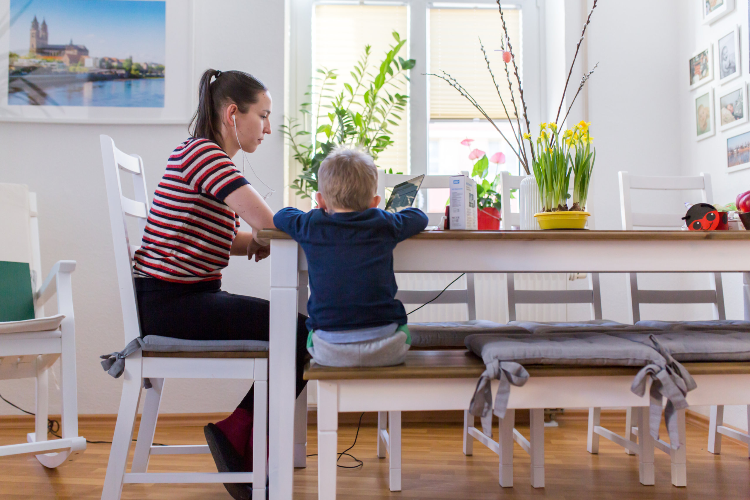 Eine Mutter arbeitet an ihrem Küchentisch, während sie auf ihr Kind aufpasst. In Österreich arbeiten deutlich mehr Frauen als Männer in Teilzeit.