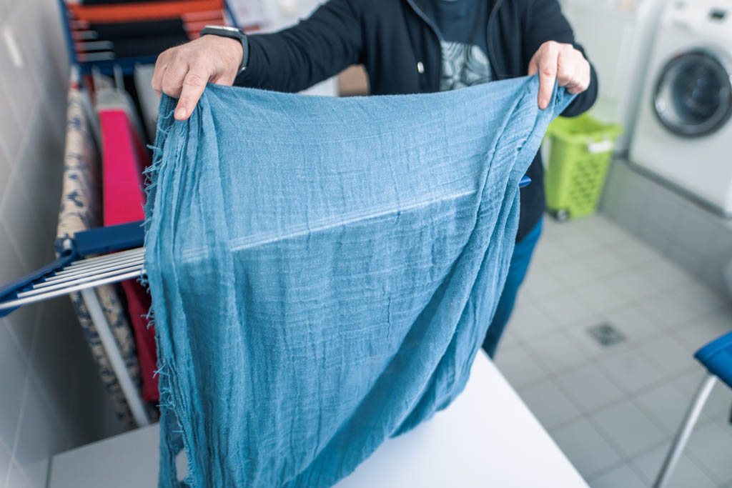 Eine Frau hängt einen Schal auf einen Wäscheständer. Symbolbild für das Frauenwohnprojekt.