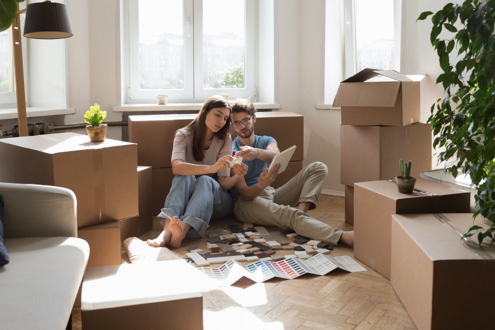 Ein Paar sitzt neben Kartons in einer neu eingerichteten Wohnung. Symbolbild für junge Menschen und Wohnen.