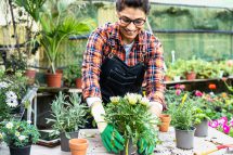 Eine Frau pflanzt in einem Gewächshaus eine Blume. In Spanien wird die 4-Tage-Woche getestet. Arbeitszeitverkürzung in Öösterreich.