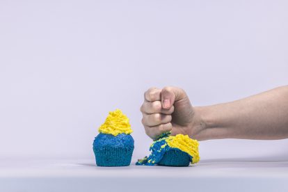 Zwei Muffins mit Europa-Flagge. Eine wird von einer Faust zerdrückt. Symbolbild für die EU.