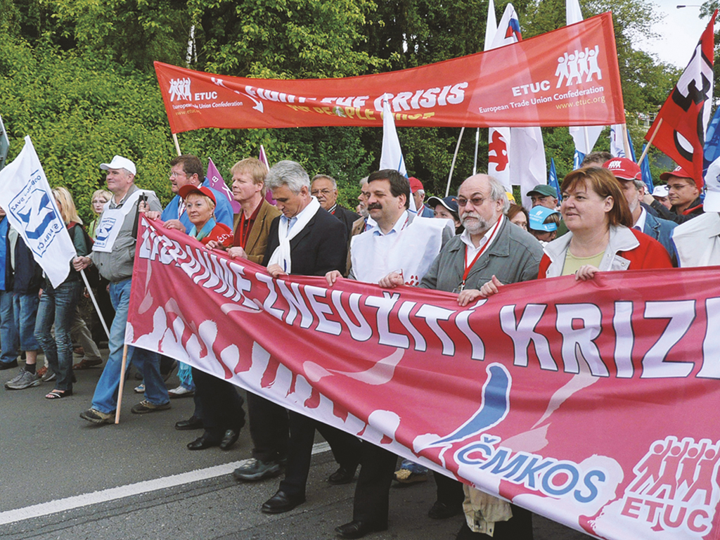 Menschen mit Bannern und Fahnen marschieren im Rahmen einer Demonstration. Symbolbild für die Protestaktionen des EGB.