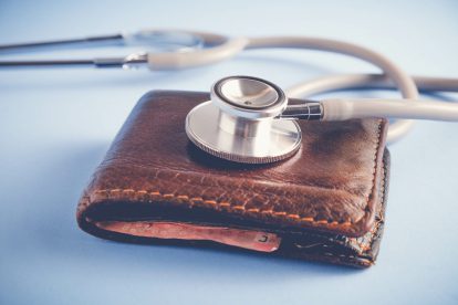 Ein Stethoskop liegt auf einer Geldbörse. Symbolbild für die Verbindung von Einkommen und Gesundheit.