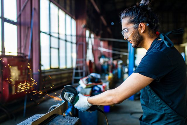 Ein Mann mit Schutzbrille arbeitet mit einem Winkelschleifer.