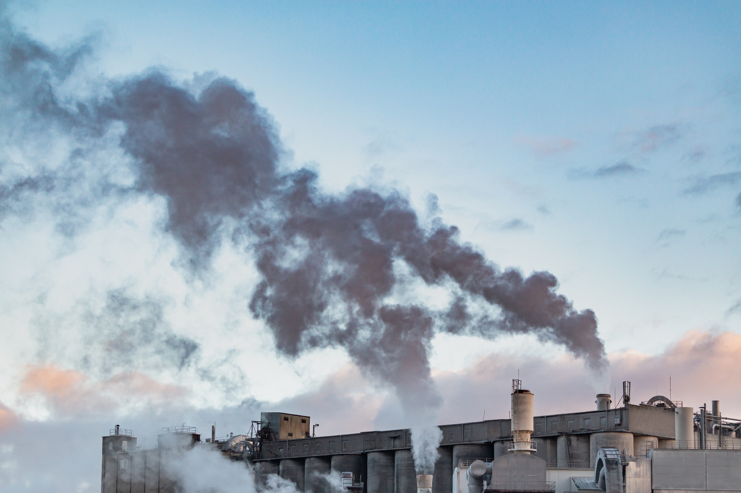 Bild von einer Anlage für fossile Energie. Rauch kommt aus einem Kamin.