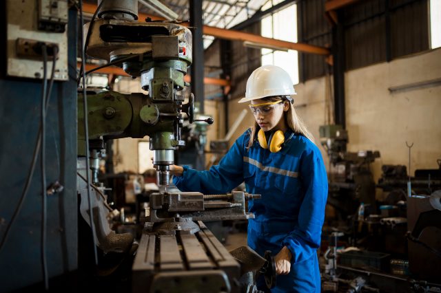 Eine Frau arbeitet an einer Maschine. Symbolbild für die Forderung nach mehr Frauen in technischen Lehrberufen.