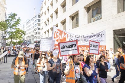 Eine Demo der Freizeitpädagog:innen. Sie tragen Schilder mit der Aufschrift "So nicht" und gehen vor einem Banner der Organisation Bildung im Mittelpunkt. Symbolbild für die Gefahr, in der die Freizeitpädagogik schwebt.