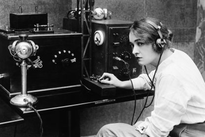 Eine Frau sitzt an einem Telegrafen und tippt einen Morsecode. Symbolbild für sich wandelnde Technologie in Mobilität und Kommunikation.