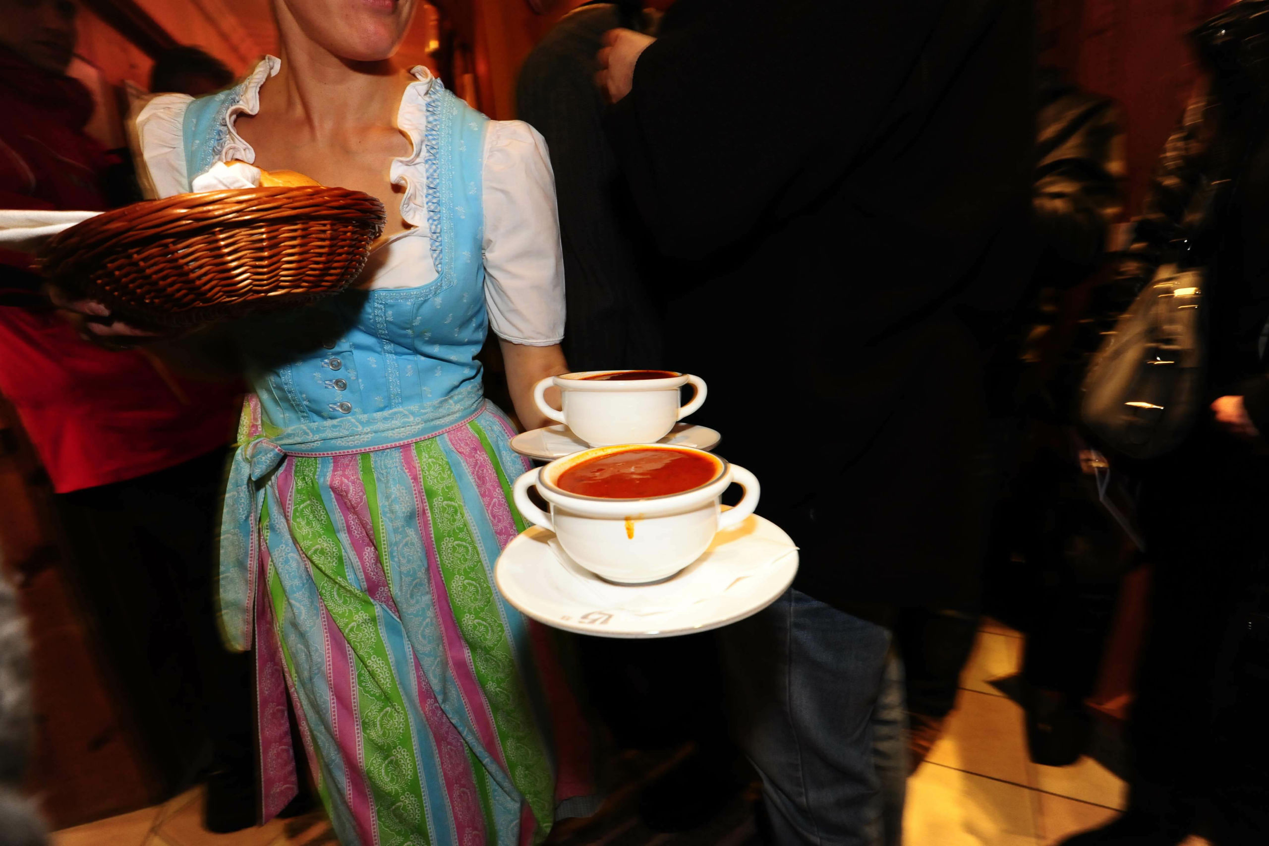 Eine Kellnerin in österreichischer Tracht serviert Gulasch. Symbolbild für die Rot-weiß-rot-Karte.