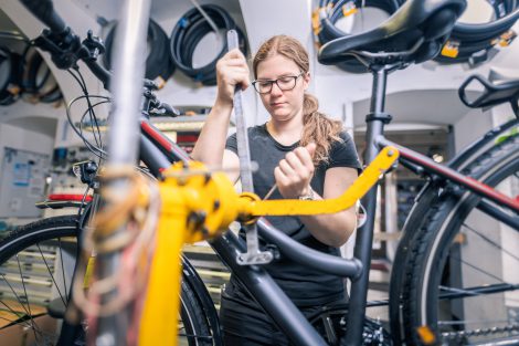 Sarah Sutlovic arbeitet an einem Fahrrad mit gelben Rahmen.