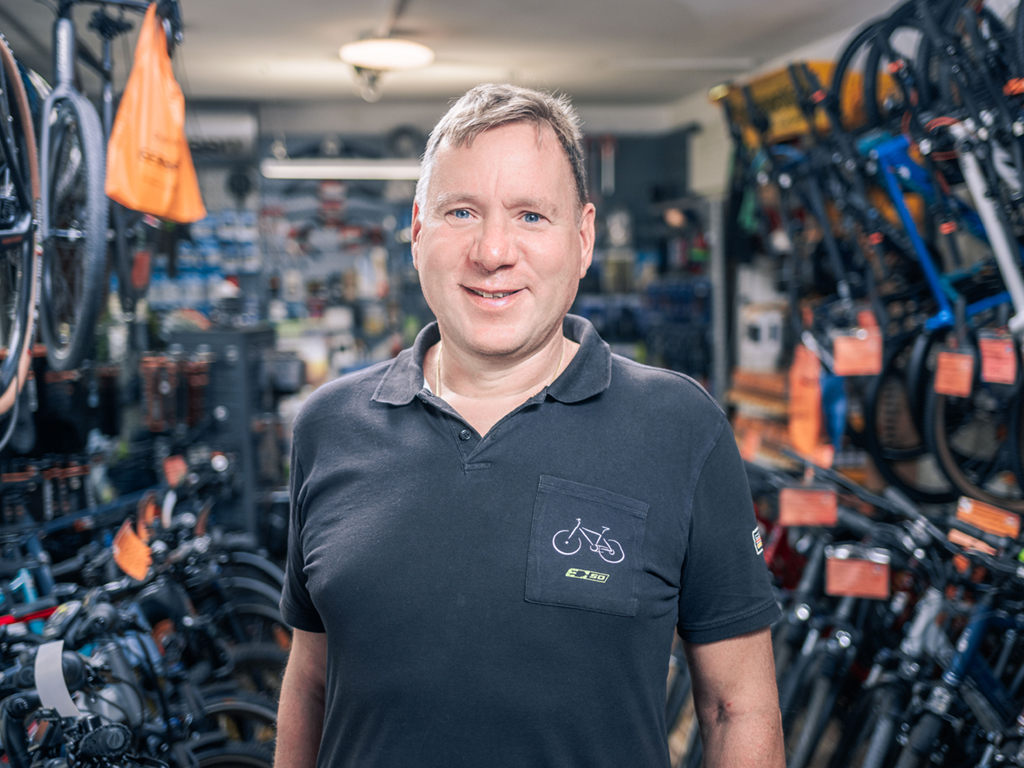 Thomas Gerhardt steht in seiner Fahrradwerkstatt und blickt lächelnd in die Kamera.