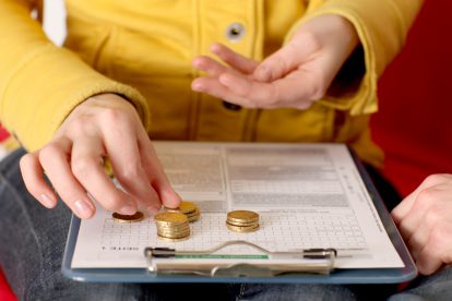 Eine Frau zählt ihr Kleingeld und stapelt die Münzen auf einem Antrag für das Arbeitslosengeld in Österreich.