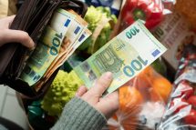 Eine Kundin in einem Supermarkt übergibt das Geld für Ihren Einkauf. Symbolbild für die Inflation in Österreich.